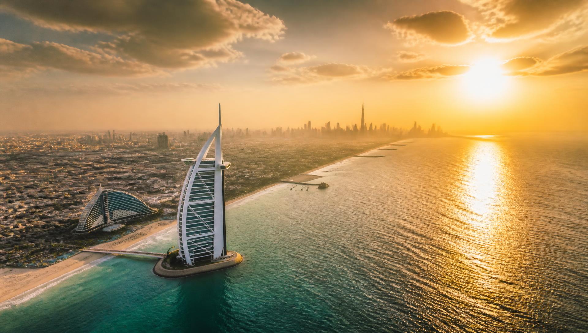 Coastline meeting a city skyline at golden hour, seen from the air